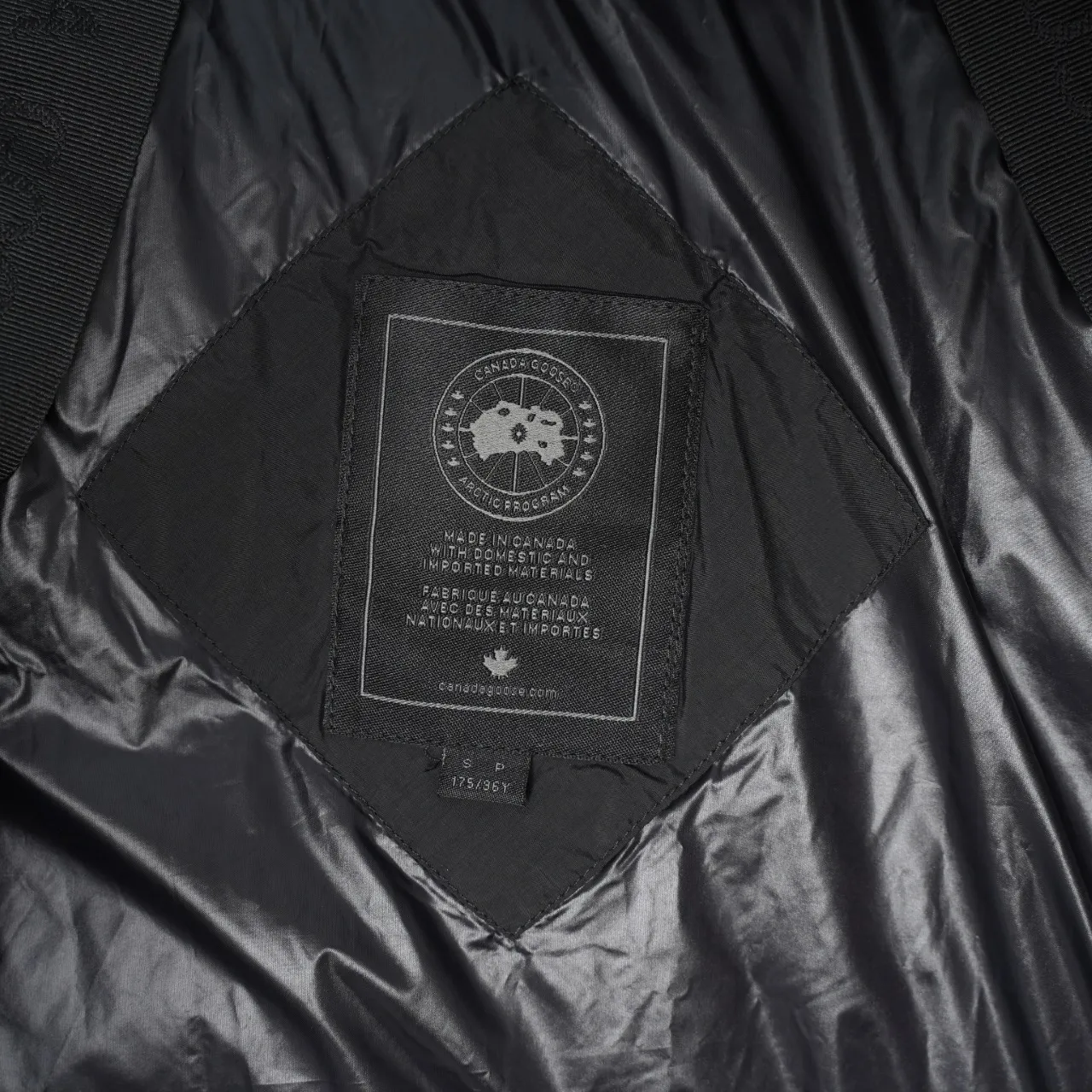 P940 Canada Goose Lawrence Down Jacket The Lawrence Down Jacket provides essential protection for everyday adventures and is made from sustainable Enduraluxe fabric with a durable soft touch. It features a quilted body, an adjustable down hood and a longer hem. Adjustable, down-filled, communicated hood. Two-way center front zipper increases range of motion and ventilation. The chin-protecting suede knit stand-up collar is soft and extra-comfortable. Inset rib-knit cuffs for added comfort and locked in heat. CORDURAD piping at the cuffs hem and reflective double-stripe grip tape at the back. Internal shoulder strap Color: black with red label black with black label azure blue Size: XS-2XL